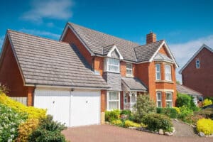 A large brick house with a driveway, garage, and a well-maintained roof.